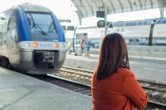 Train arrivant en gare, femme de dos en premier plan