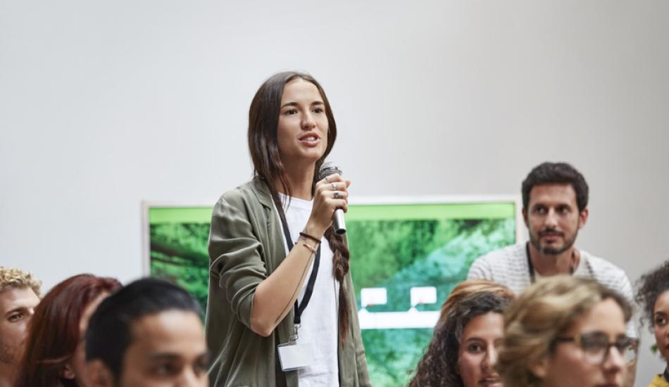 jeune femme prenant la parole dans le cadre d'une réunion publique